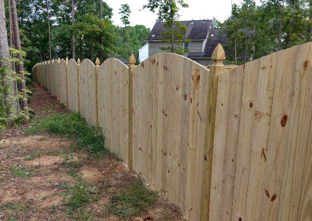 Dog-eared privacy fence along a wooded path