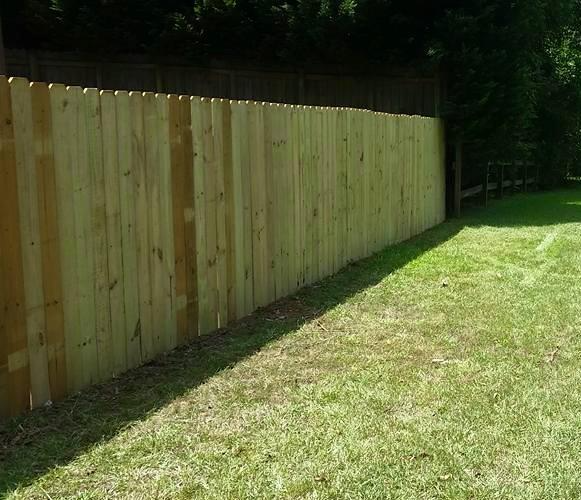Dog-eared privacy fence backing onto a lawn