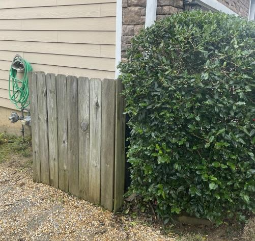 Wood fence panel screening a utility area next to a hedge