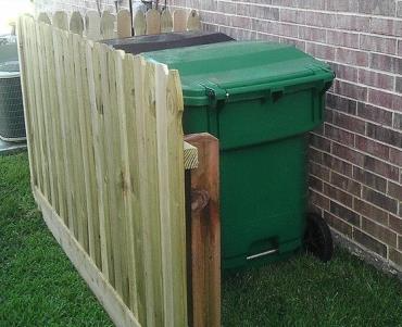 Wood fence panel screening a garbage cart